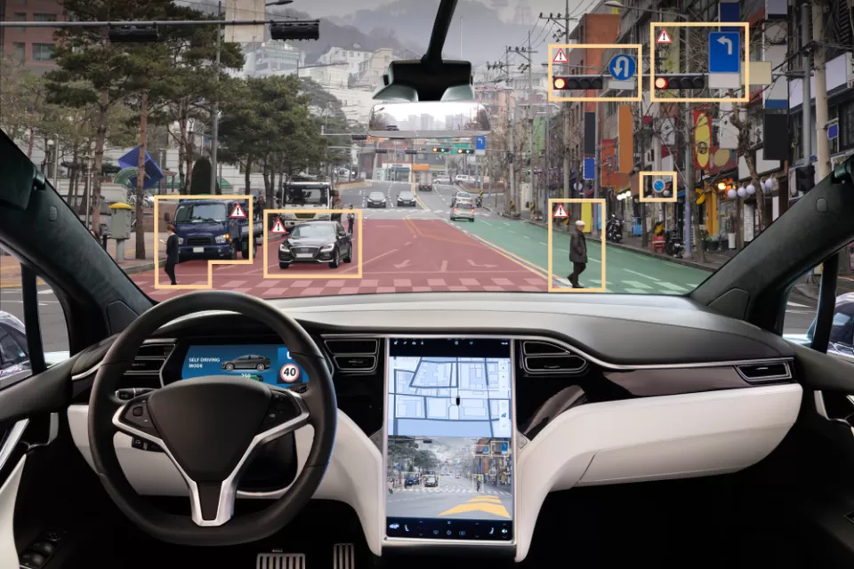 View from inside driver's seat of car with autonomous technology, with yellow rectangles highlighting obstacles in road